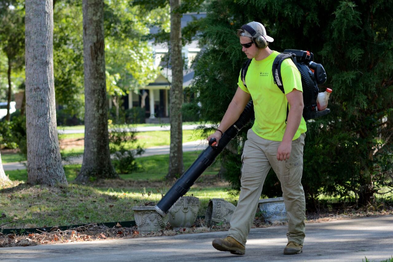 Lawn care technician clearing a walkway with a backpack blower