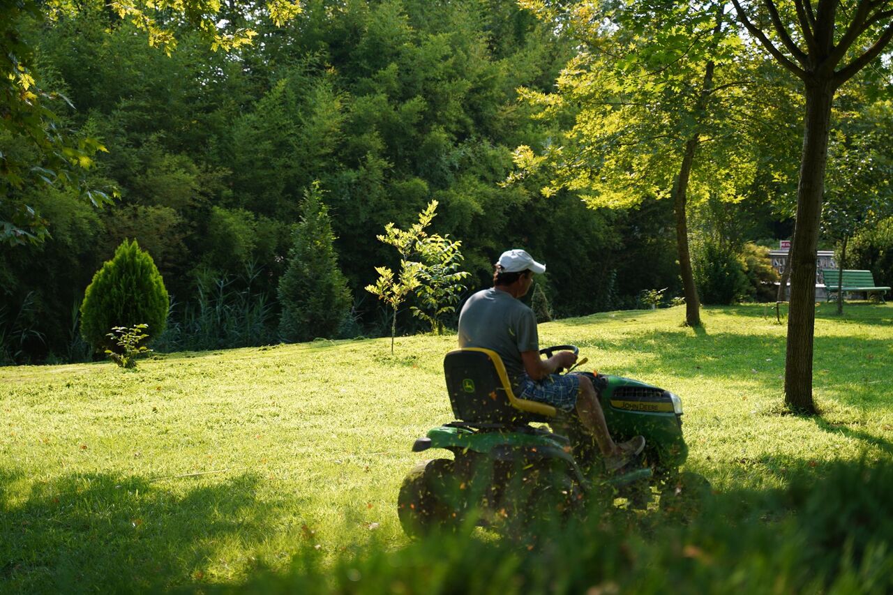 Riding mower cutting a residential lawn on a sunny afternoon